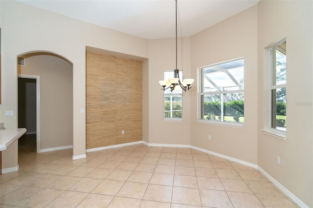 unfurnished dining area with a notable chandelier, a healthy amount of sunlight, and light tile patterned floors