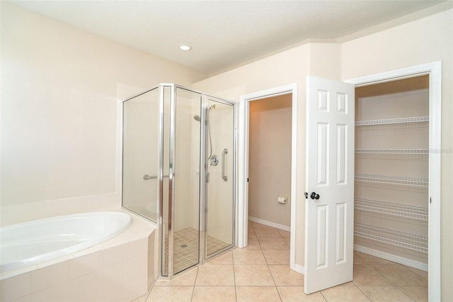 bathroom with tile patterned flooring, a spacious closet, a bath, and a stall shower