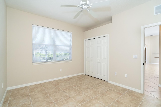 unfurnished bedroom with visible vents, ceiling fan, baseboards, light tile patterned floors, and a closet