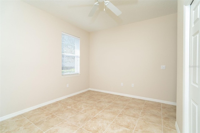 empty room with light tile patterned flooring, a ceiling fan, and baseboards