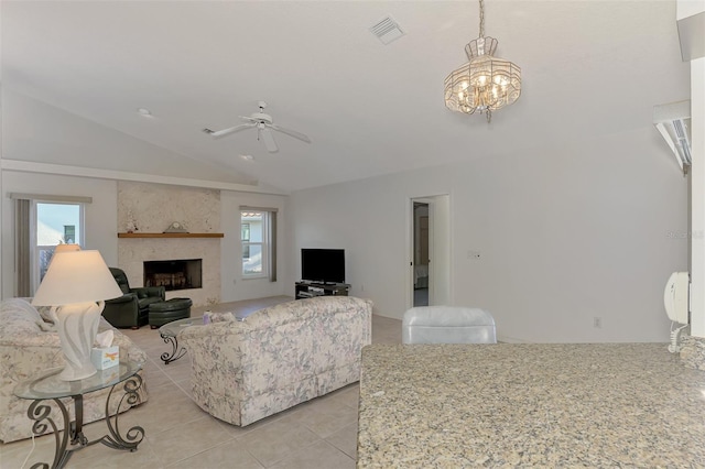 living room featuring ceiling fan with notable chandelier, vaulted ceiling, a large fireplace, and light tile patterned flooring