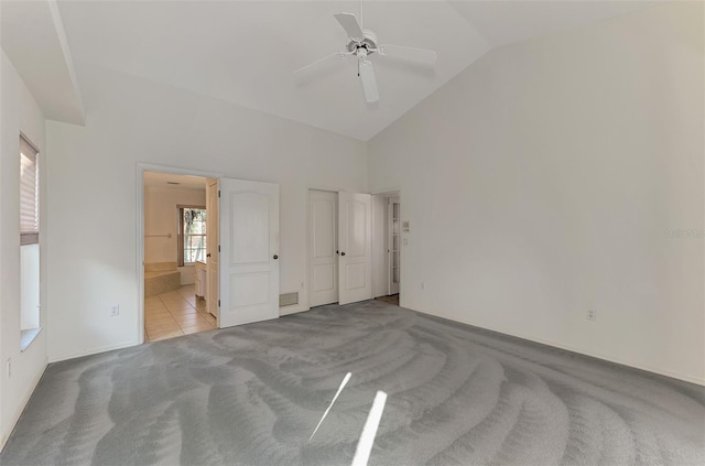 unfurnished bedroom featuring light carpet, high vaulted ceiling, ceiling fan, and ensuite bathroom