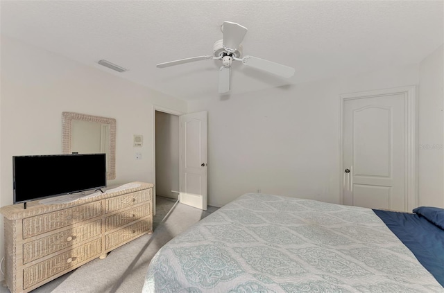 carpeted bedroom featuring ceiling fan and a textured ceiling