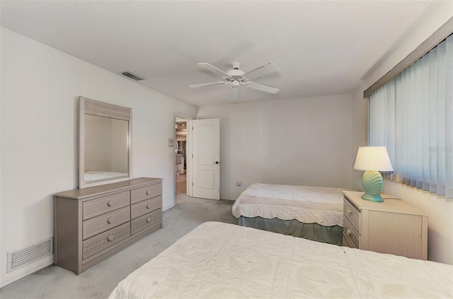 carpeted bedroom featuring ceiling fan and a textured ceiling