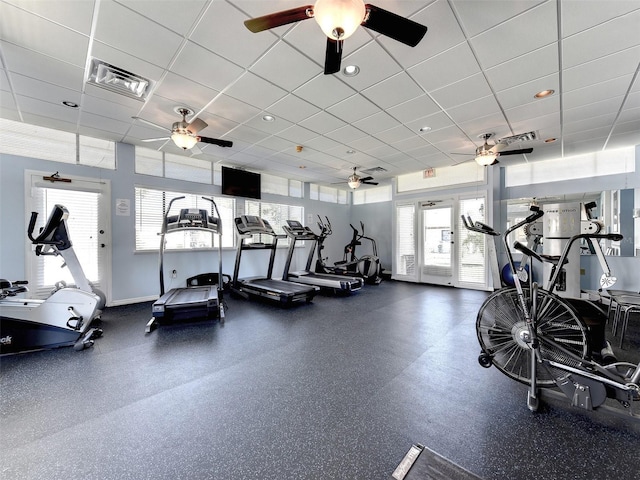 exercise room with a paneled ceiling and a healthy amount of sunlight