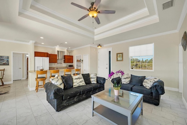 living room featuring a raised ceiling, crown molding, sink, and ceiling fan