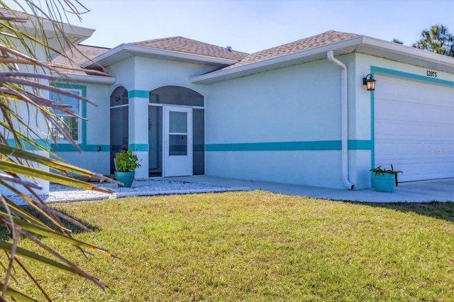 view of exterior entry with a garage and a yard