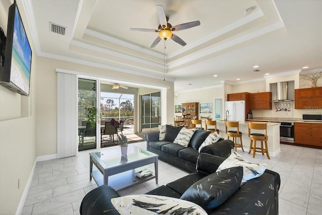 living room featuring crown molding, ceiling fan, and a tray ceiling