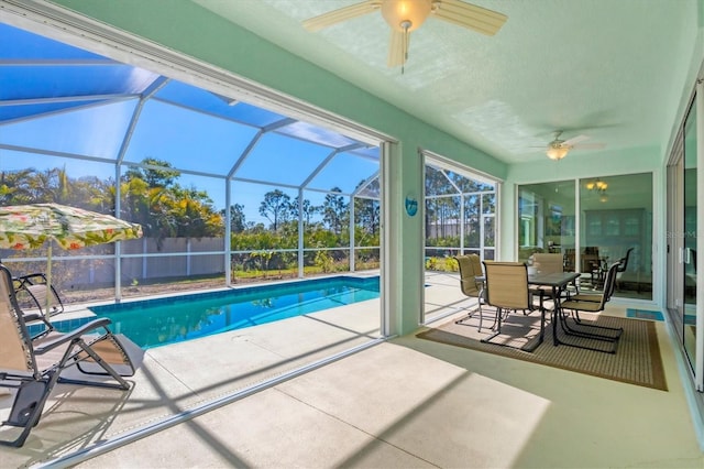 view of pool with a patio, ceiling fan, and glass enclosure