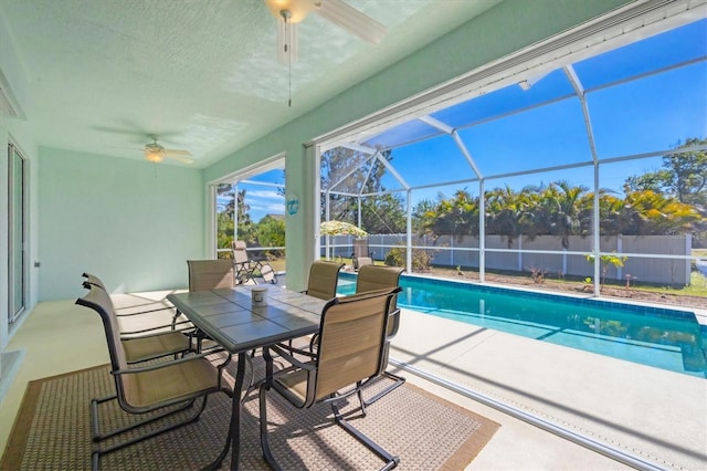 view of swimming pool with ceiling fan, a patio, and glass enclosure