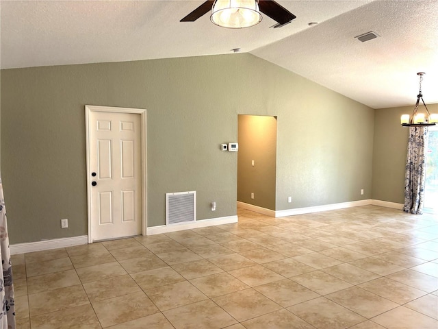 tiled spare room with vaulted ceiling, ceiling fan with notable chandelier, and a textured ceiling