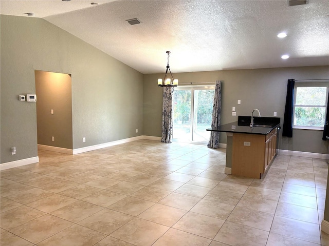 kitchen featuring lofted ceiling, sink, light tile patterned floors, a notable chandelier, and pendant lighting