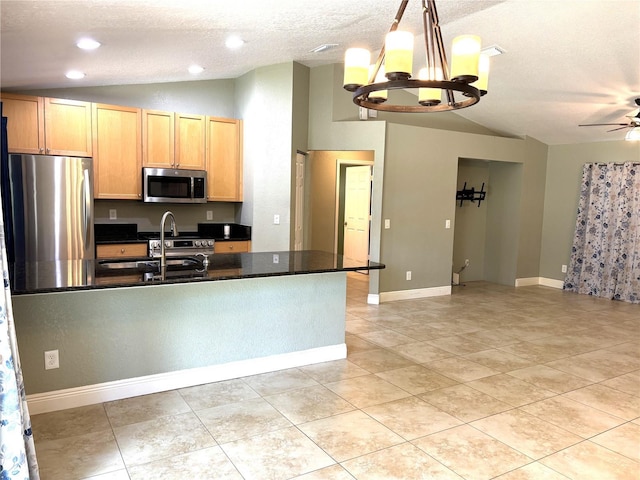 kitchen with sink, decorative light fixtures, vaulted ceiling, stainless steel appliances, and ceiling fan with notable chandelier