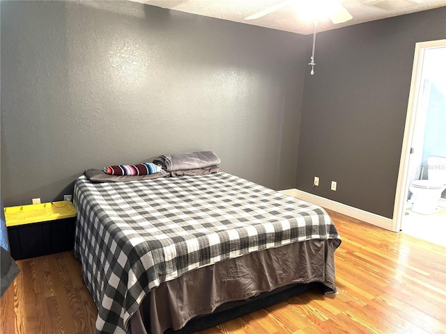 bedroom with ensuite bath and hardwood / wood-style floors