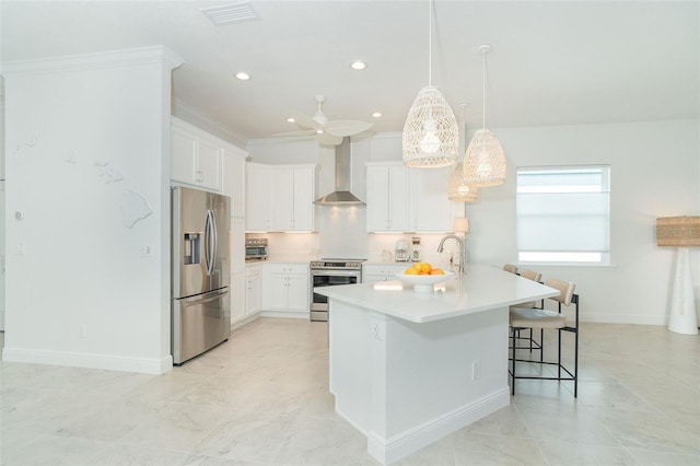 kitchen featuring white cabinets, hanging light fixtures, ornamental molding, stainless steel appliances, and wall chimney exhaust hood