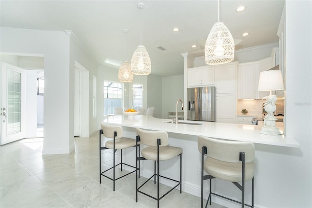 kitchen featuring decorative light fixtures, sink, white cabinets, kitchen peninsula, and stainless steel refrigerator with ice dispenser