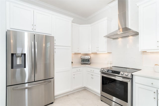 kitchen featuring white cabinetry, ornamental molding, appliances with stainless steel finishes, and wall chimney range hood