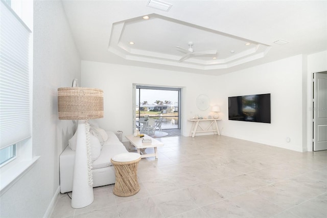 living area featuring ceiling fan and a tray ceiling