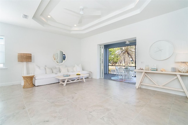 living room with a raised ceiling, a high ceiling, and ceiling fan