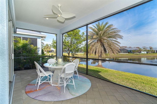 sunroom / solarium featuring ceiling fan and a water view