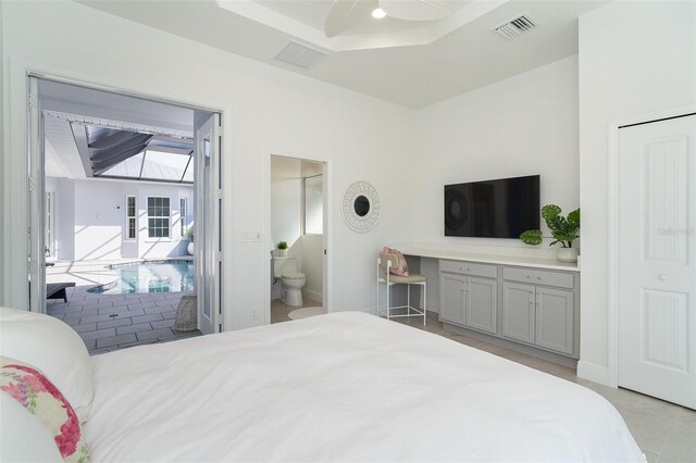 bedroom featuring ensuite bathroom, ceiling fan, and a tray ceiling