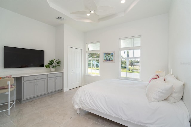 bedroom with ceiling fan, a raised ceiling, a closet, and a high ceiling