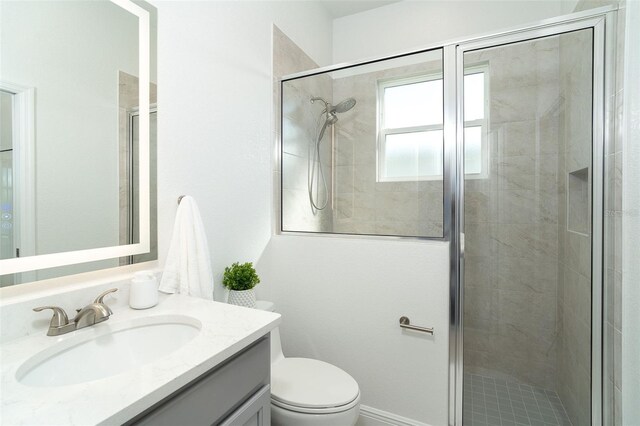 bathroom featuring vanity, a shower with door, and toilet