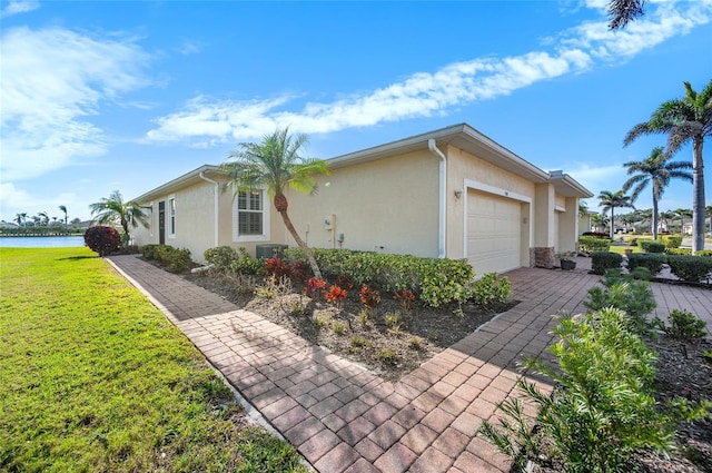 view of front facade featuring a garage, a water view, cooling unit, and a front yard