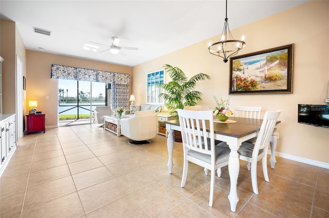 tiled dining area featuring ceiling fan with notable chandelier and a water view