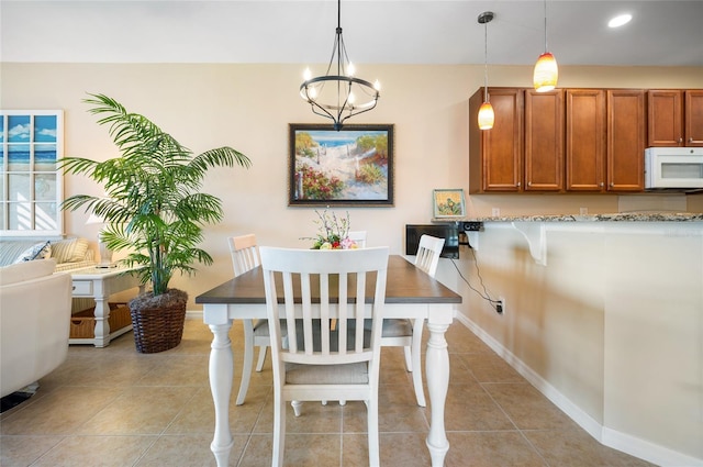 tiled dining room with a chandelier