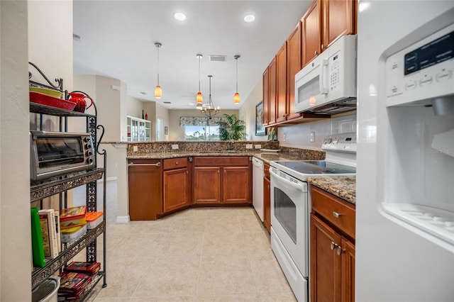 kitchen with pendant lighting, dark stone countertops, light tile patterned floors, kitchen peninsula, and white appliances