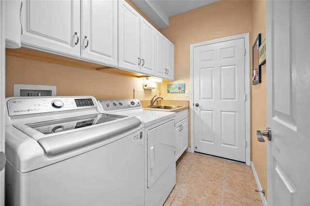 laundry room with cabinets, washer and clothes dryer, sink, and light tile patterned floors