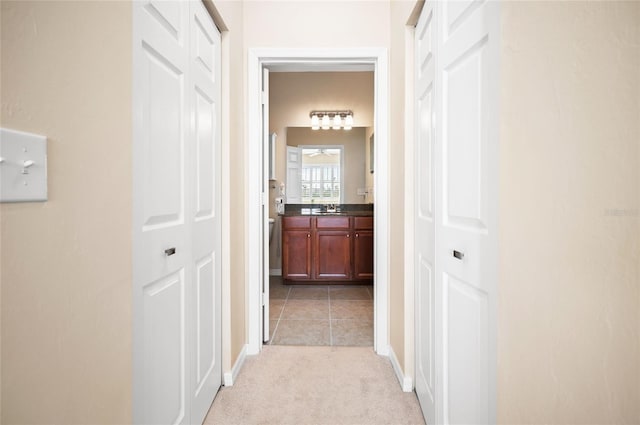 corridor featuring sink and light colored carpet