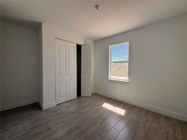 unfurnished bedroom with a closet, baseboards, and dark wood-style floors