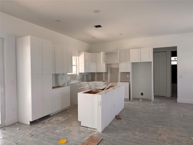 kitchen featuring light wood-style flooring, a kitchen island, and white cabinets