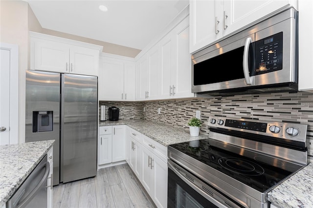 kitchen featuring stainless steel appliances, white cabinets, and light stone counters