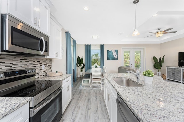 kitchen featuring white cabinetry, sink, decorative backsplash, stainless steel appliances, and light stone countertops