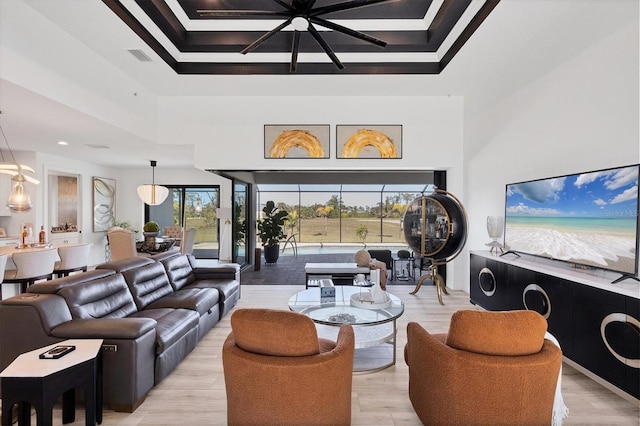 living room featuring a towering ceiling, light hardwood / wood-style floors, and a raised ceiling