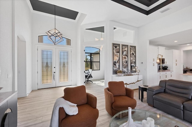 living room featuring a towering ceiling, light hardwood / wood-style flooring, and french doors