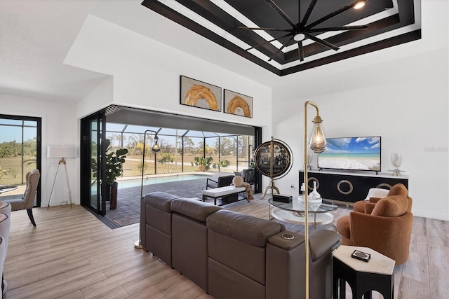 living room with a high ceiling, plenty of natural light, and light hardwood / wood-style floors