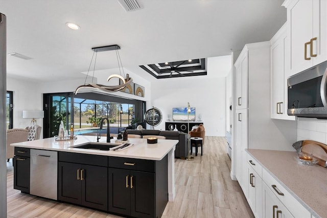 kitchen featuring white cabinetry, appliances with stainless steel finishes, sink, and an island with sink