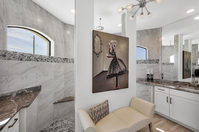 bathroom with hardwood / wood-style flooring, tiled shower, vanity, and a wealth of natural light