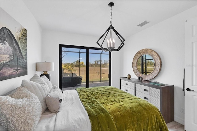 bedroom with access to exterior, a notable chandelier, and hardwood / wood-style floors