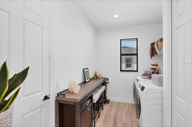 clothes washing area with washing machine and clothes dryer and light wood-type flooring