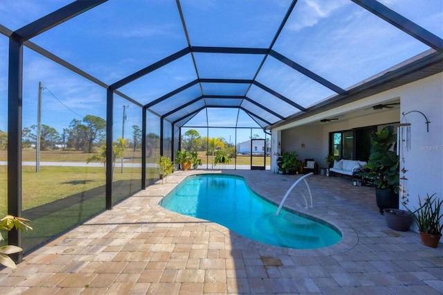 view of swimming pool with a yard, a patio, ceiling fan, and glass enclosure