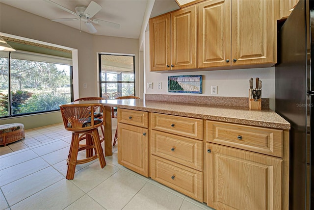 kitchen with black refrigerator, light tile patterned floors, and ceiling fan