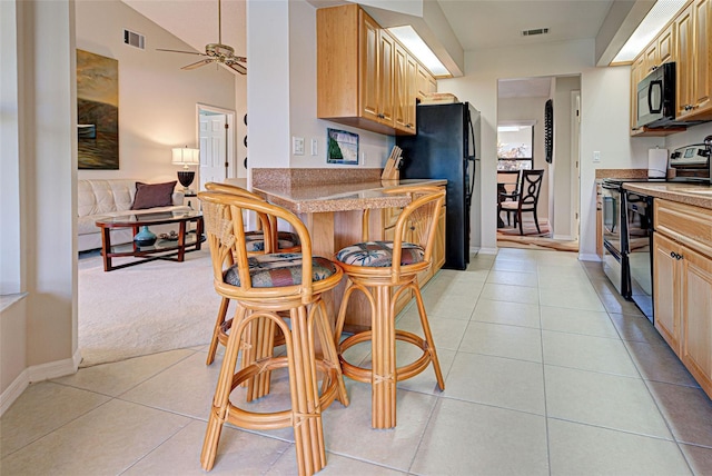 kitchen with vaulted ceiling, light tile patterned floors, ceiling fan, black appliances, and light brown cabinets