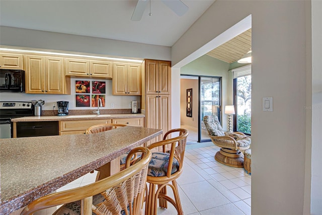 kitchen featuring lofted ceiling, sink, light tile patterned floors, light brown cabinets, and electric range