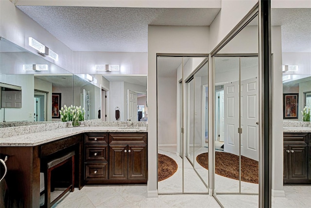 bathroom with tile patterned flooring, vanity, and a textured ceiling