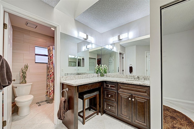 bathroom with tile patterned flooring, vanity, toilet, and a textured ceiling